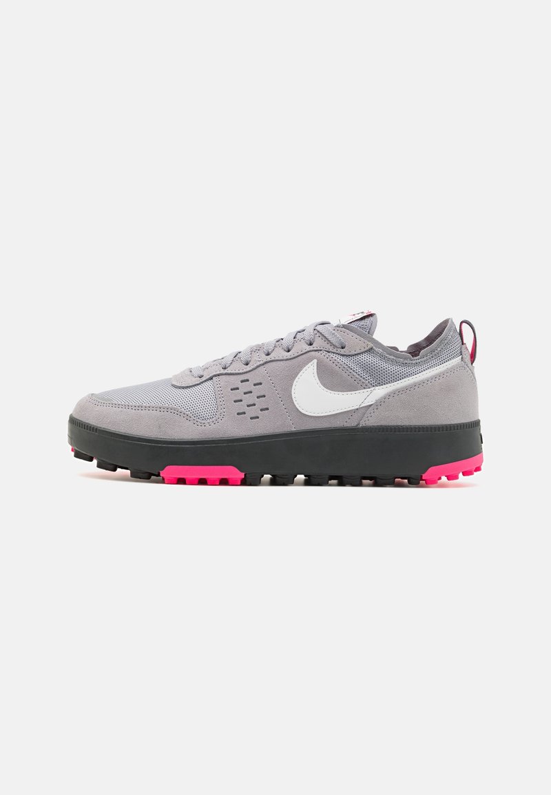 Gray sneaker featuring a combination of mesh and suede materials, white logo, black outsole with a bright pink accent. Textured design details.