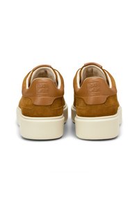 Scarpe in suede marrone con un accento in pelle beige sul tacco e suole in gomma bianca, dotate di un logo impresso sul retro e rivestimento in morbido tessuto.