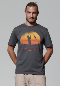 Grau T-Shirt aus Baumwolle mit einem orange- und gelbfarbenen Angelmotiv, das einen Sonnenuntergang und Silhouetten von Fischen zeigt. Kurzärmlig mit Rundhalsausschnitt.