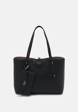 Sac fourre-tout en cuir noir texturé avec deux anses et une pochette détachable assortie, tous deux marqués du logo "GUESS EST 1981" en lettres dorées.