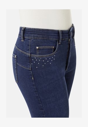 Dunkelblaue Denim-Jeans mit schlankem Schnitt, ausgestattet mit metallischen Akzenten und dekorativen Strasssteinen auf der Gesäßtasche.