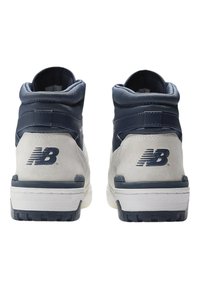 High-top sneakers in navy and gray suede, featuring a padded collar, white midsole, and prominent "N" logo on the heel.