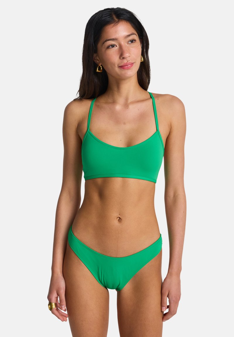 Σετ πράσινου μπικίνι που περιλαμβάνει σουτιέν χωρίς ενίσχυση και σλιπ χαμηλής μέσης. Κατασκευασμένο από λείο, ελαστικό υλικό με λεπτές τιράντες.