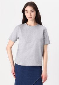 Tricou gri cu mânecă scurtă, realizat dintr-un material de bumbac moale. Are un guler clasic rotund și o croială lejeră, ușor scurtă.