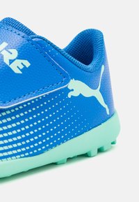 Blue soccer shoe with textured synthetic material, mesh sock collar, light blue outsole, and white Puma logo. Features diagonal stripe pattern.