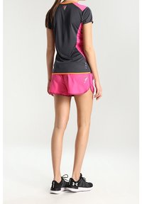 Camiseta atlética gris y rosa con detalles en naranja, combinada con pantalones cortos rosas y zapatillas de running negras, con un diseño ligero y transpirable.