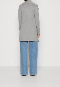 Gray long-sleeve top with a relaxed fit, paired with light blue wide-leg jeans, both featuring soft fabric and minimal detailing.