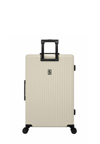 Harde koffer in beige, met verticale groeven, een uitschuifbare zwarte handgreep en vier zwarte wielen voor mobiliteit.