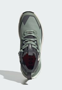 Groene en grijze sportschoen met een gestructureerde bovenkant, gebogen ontwerp, vastgemaakte veters en een gelabelde trekband aan de hiel.