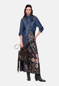 Denim blouse with a bow tie, floral patterned, satin skirt, and brown bucket bag. Black heeled boots with fringe details.