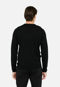 Pulover negru din material moale, cu guler rotund, mâneci lungi și manșete și tiv striate. Design simplu, fără modele sau embellishments.
