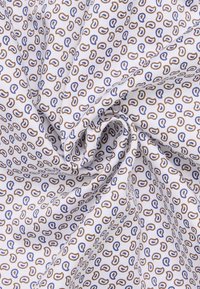Katoenen stof met een klein herhaalpatroon van bruine en blauwe druppelvormen op een witte achtergrond, met een soepele textuur.
