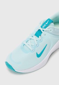 Světle modrá sportovní bota s prodyšným síťovaným svrškem, bílou podrážkou a kontrastními tyrkysovými akcenty. Obsahuje šněrovací design a výrazné logo Nike.