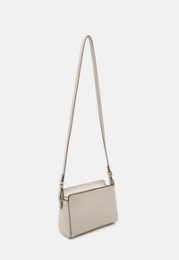 Bolso bandolera de piel beige con correa ajustable, forma rectangular, superficie lisa y ribetes negros en los bordes y en la cremallera.