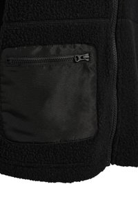 Czarna kurtka z polaru z gładką, zamykaną na zamek kieszenią po lewej stronie oraz czarnym zamkiem błyskawicznym biegnącym pionowo obok niej.