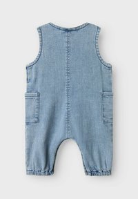 Denim kombinezon v svetlo modri barvi, brez rokavov, z stranskimi žepi, elastičnim robom in preprostim šivom na hrbtni strani. Teksturni zaključek blaga.