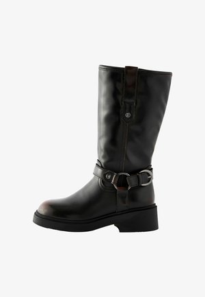 Mustmustest musta knee-high saapad mustast nahast, millel on klamber, ümar jooks ja tekstuuriga viimistlus. Omab madalat, paksu kuulti ja õmblemise aktsente.