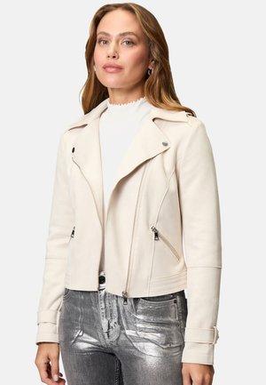 Veste de motard en faux daim crème avec poches zippées, revers crantés et silhouette ajustée, assortie à un jean argenté brillant.
