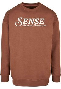 Brun sweatshirt med rund halsringning, med vit text "SENSE BLAZING HORIZON" på framsidan, tillverkad av mjukt, strukturerat tyg.