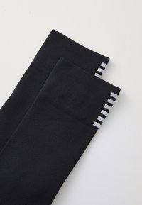 Black athletic socks made of breathable fabric, featuring a textured pattern and white accent stripes on the top edge.
