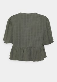 Green blouse with a textured fabric, short sleeves, and a ruffled hem. Features a square neckline and a subtle checked pattern.