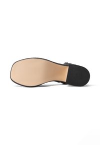 Soletta nera con uno strato inferiore beige liscio, dotata di tomaia in tessuto nero testurizzato. Il design è piatto con una forma arrotondata.