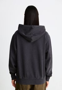 Dark gray hooded sweatshirt with a relaxed fit, featuring a kangaroo pocket, ribbed cuffs, and hem, made from textured cotton material.