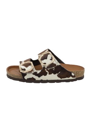 Brown and white cow-print slide sandals with two adjustable straps, textured upper, cork footbed, and rubber sole, featuring gold-tone accents.