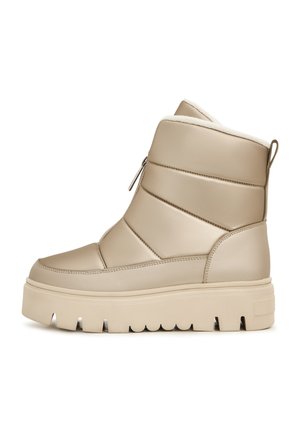 Beige polstret ankelsko med en glat finish, udstyret med en sidelukning og en tyk, rillede sål med et tekstureret mønster.