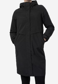 Long manteau noir imperméable avec capuche, coupe droite, poches avant et tissu lisse et texturé. Design minimaliste.