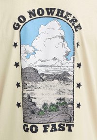 Έρημος με βραχώδεις σχηματισμούς, πράσινα φυτά, γαλάζιο ουρανό, λευκά σύννεφα και το κείμενο «ΜΗΝ ΠΗΓΑΙΝΕΙΣ ΠΟΥΘΕΝΑ» πάνω και «ΠΗΓΑΙΝΕ ΓΡΗΓΟΡΑ» κάτω.