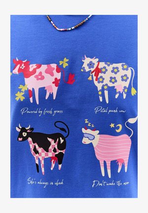 Modrá látka zobrazuje čtyři kreslené krávy s různými vzory: růžová s květinovým potiskem, černá s kostkovaným vzorem a růžová pruhovaná kráva se spací maskou.