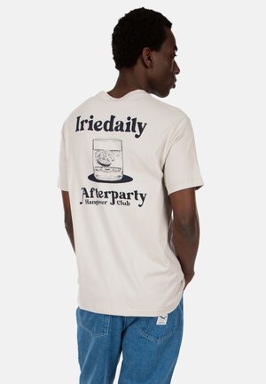 Beige Baumwoll-T-Shirt mit einem grafischen Design eines Glases mit Blasen und dem Aufdruck "Iriedaily Afterparty Club" in Marineblau.