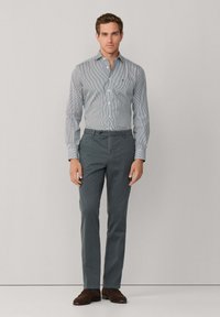 Lichtgestreepte blauw-witte shirt met een button-down kraag, gecombineerd met effen grijze broek en bruine schoenen.