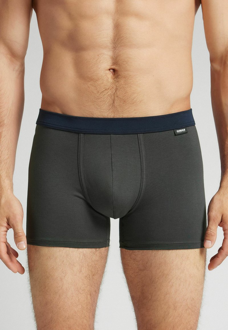 Šedé boxerky s námořnickým elastickým pasem, vyrobené z hladkého materiálu. Mají přední kapsu a ploché švy pro větší pohodlí.