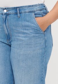 Light blue denim jeans with a high waist, featuring a front pocket, zipper closure, and subtle stitching details. Smooth texture.