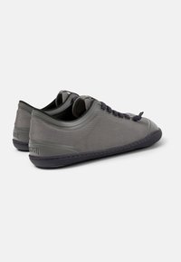 Szare siateczkowe sneakersy o niskim profilu, teksturowanej cholewce, z zapięciem na sznurowadła i kontrastującą ciemną podeszwą. Trwała i lekka konstrukcja.
