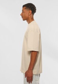 Beige T-shirt met korte mouwen in een ontspannen pasvorm, gemaakt van zachte katoen, met een ronde hals en een glad, onbewerkt oppervlak.