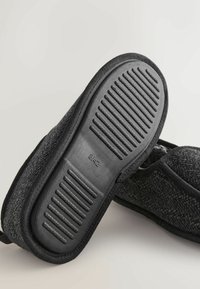 Pantofole nere con una tomaia intrecciata e testurizzata e una suola in gomma con righe orizzontali per una migliore aderenza. Taglia stampata sulla suola: 41/42.