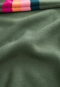 Tessuto verde testurizzato con un fine punto a costine, caratterizzato da strisce multicolori di rosa, arancione e teal lungo il bordo superiore.