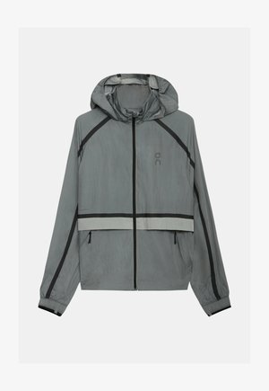 Jachetă ușoară gri deschis cu glugă, fermoar negru, accente negre și reflectorizante, manșete elastice și buzunare laterale cu fermoar.