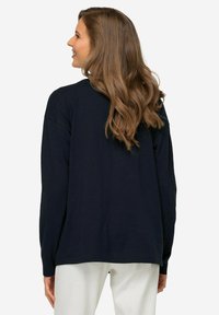 Granatowa koszulka z długim rękawem, okrągły dekolt, luźny krój, miękki materiał, minimalistyczny design, brak widocznych grafik czy elementów metalowych, gładka faktura.