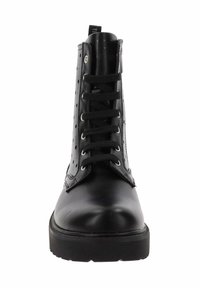 Botín negro con cordones, de tobillo, con lados perforados, punta redonda, suela gruesa y cordones negros. Acabado en piel suave con ojales metálicos.