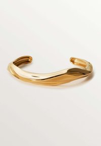 Pulsera de brazalete en tono dorado con un diseño ondulado y liso, acabado ligeramente reflectante y extremos abiertos para un ajuste ajustable.