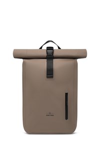 Beige, vízálló anyagból készült roll-top hátizsák. Fekete csattal záródik, oldalsó cipzáras zsebe van, és a könnyebb hordozhatóság érdekében tetején fogantyú található.