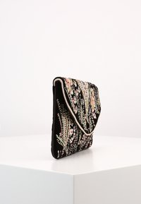 Bolso de mano de terciopelo negro con bordado floral en rosa y verde, que presenta un diseño de solapa y ribete contrastante a lo largo del borde.