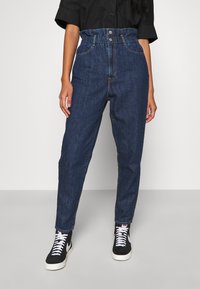 Mörkblå denimjeans med hög midja, resårmidja med samling, knappstängning och framfickor. Slät textur och smal benpassform.