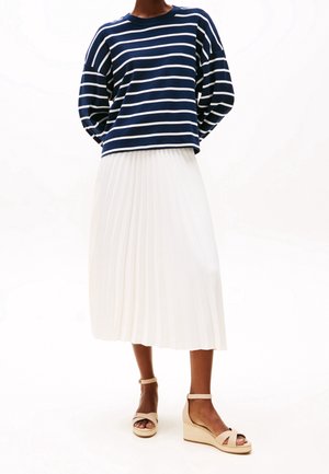 Navy i biały w paski top z długim rękawem, plisowana biała spódnica midi oraz beżowe sandały na koturnie. Skup się na fakturach materiału i kształtach.