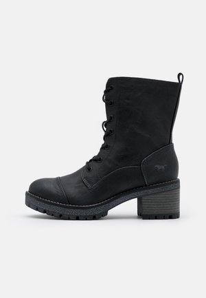 Bottines en cuir noir avec une finition texturée, à lacets à l'avant, bout rond et talon épais. Présente une semelle grise contrastante et un logo discret.