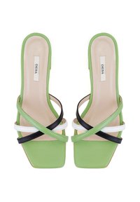 Mules verts avec un embout carré, présentant des sangles croisées en noir et blanc. Texture lisse avec un design minimaliste et une marque discrète.